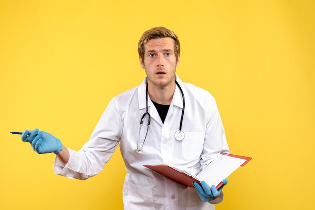 Front view male doctor writing notes on yellow desk virus health medic human