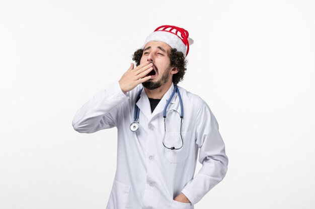 Front view of male doctor yawning on white wall