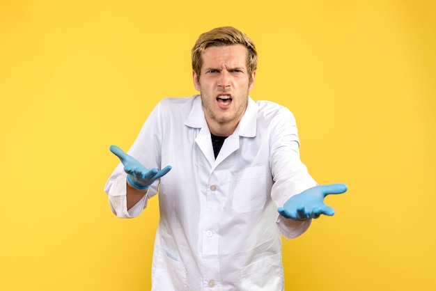 Вид спереди мужской врач на желтом фоне covid человеческий медик эмоция