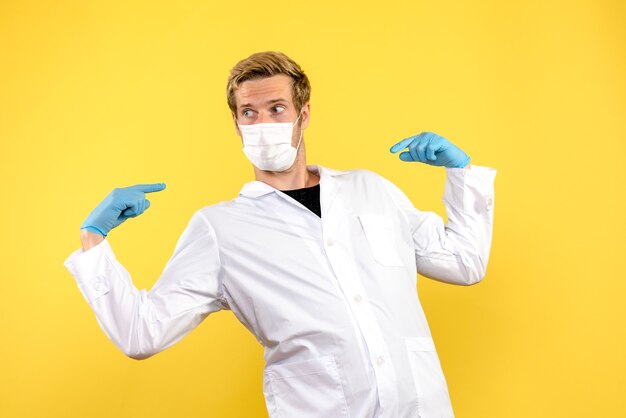 Front view male doctor on a yellow background health pandemic covid- medic