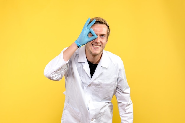 Вид спереди мужской доктор на желтом фоне медик covid- пандемия