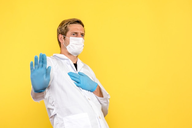 Вид спереди мужской доктор на желтом фоне пандемический медик covid- здоровье