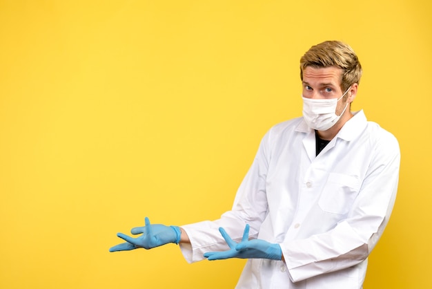 Free photo front view male doctor on a yellow desk health virus pandemic covid