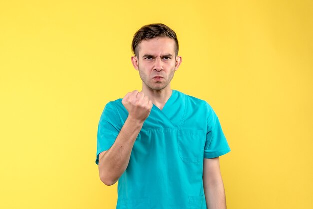 Front view of male doctor on yellow wall