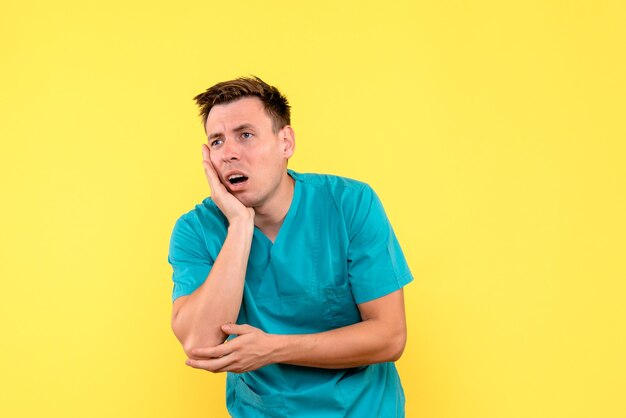 Front view of male doctor on yellow wall