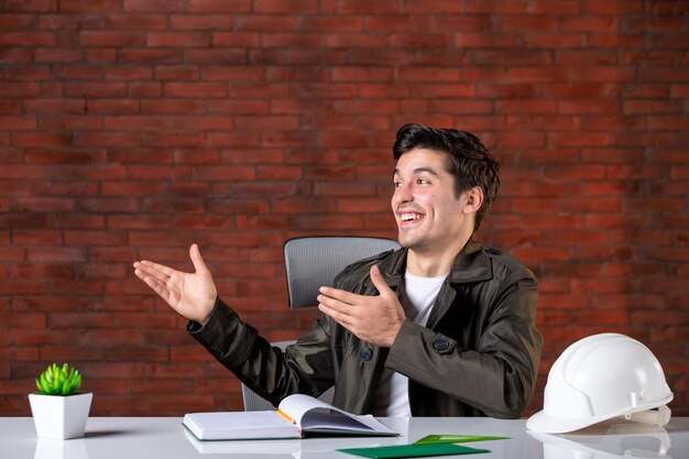 Front view male engineer sitting behind his working place job business contractor agenda document corporate builders property plan