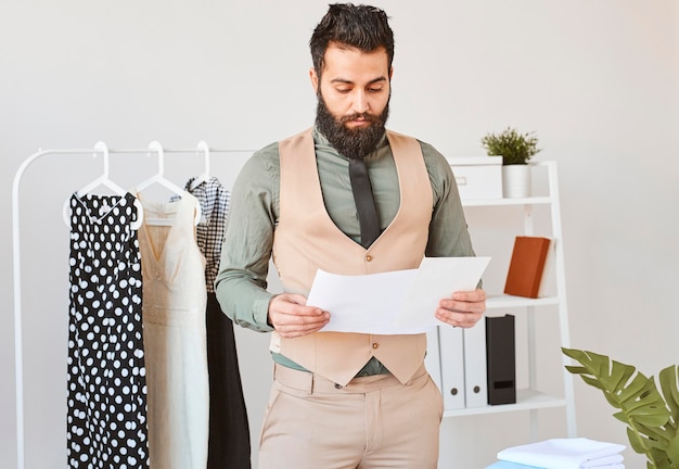 Free photo front view of male fashion designer working in atelier with papers