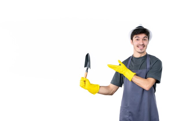 Front view male gardener in yellow gloves holding little spatula on a white background color flower tree job garden ground work bush grass