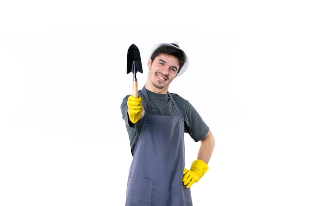 Садовник-мужчина в желтых перчатках, вид спереди, держит маленькую лопаточку на белом фоне, цвет травы, цветок, дерево, работа, земляные работы в саду