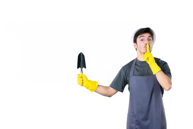 Front view male gardener in yellow gloves holding little spatula on a white background tree color flower garden ground work bush grass job