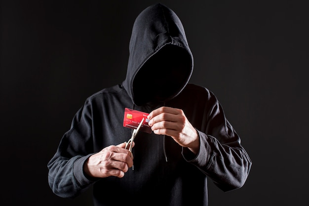 Free photo front view of male hacker cutting credit card with scissors