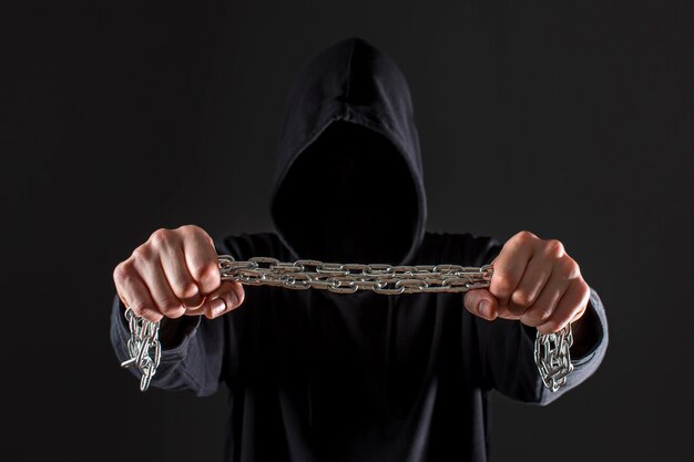 Front view of male hacker holding metal chain in hands