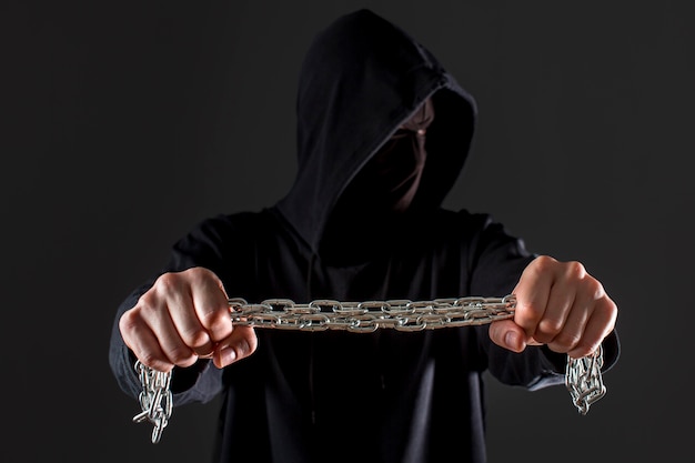 Front view of male hacker holding metal chain