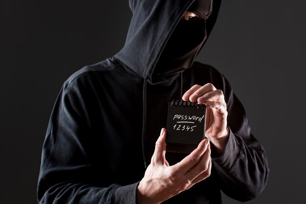 Front view of male hacker holding notebook with password