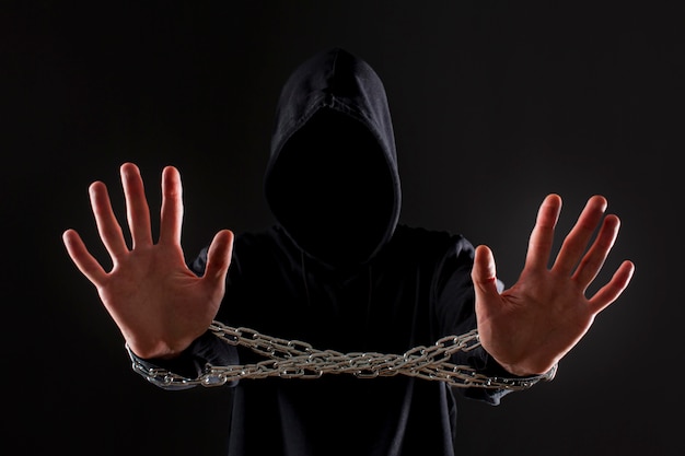 Front view of male hacker with metal chain around hands