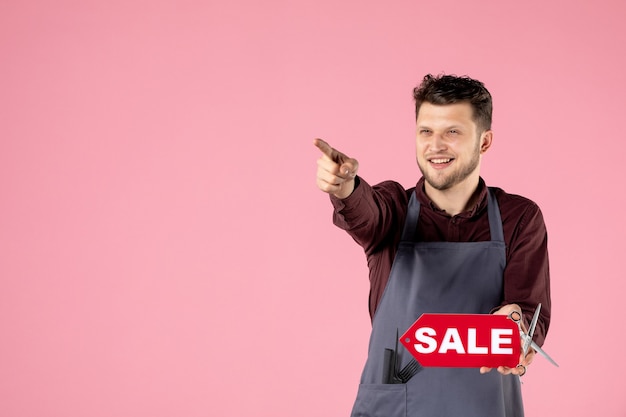 front view male hairdresser with red sale nameplate on pink background