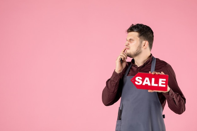 Бесплатное фото Мужской парикмахер вид спереди с табличкой продажи и ножницами на розовом фоне