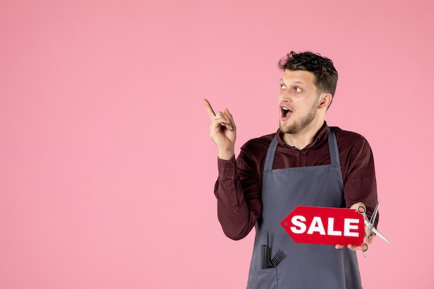 front view male hairdresser with sale nameplate on pink background