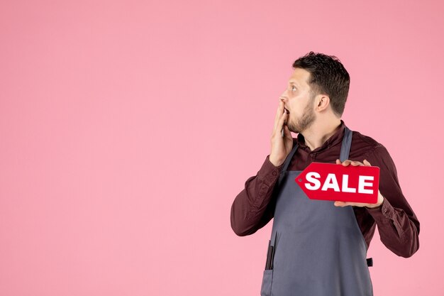 front view male hairdresser with sale nameplate and scissors on pink background