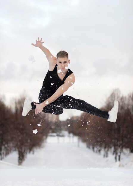 Front view of male hip hop performer posing in mid-air with snow
