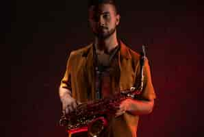 Free photo front view of male musician holding a saxophone