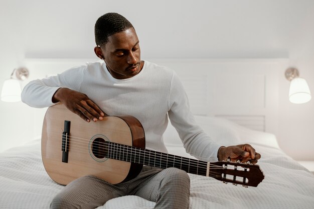 ベッドでギターを弾く男性ミュージシャンの正面図