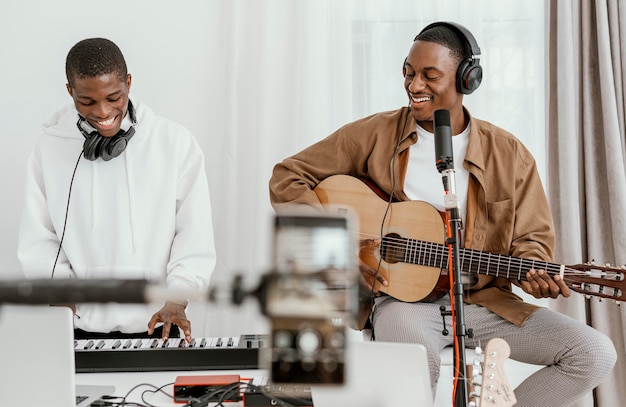 Foto gratuita vista frontale di musicisti maschi a casa a suonare la chitarra e cantare