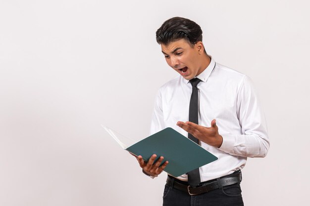 Front view male office worker checking documents on white wall male business work job