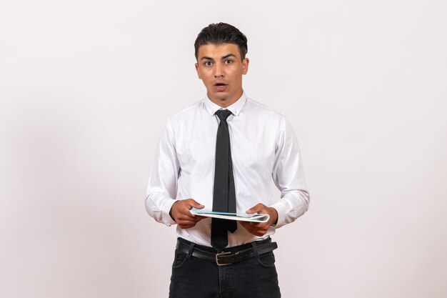 Front view male office worker holding documents on a white wall male business work job