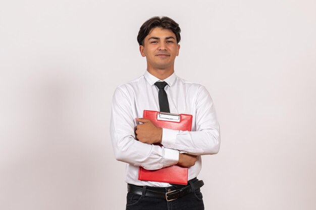 Front view male office worker holding red file on white desk office work job human