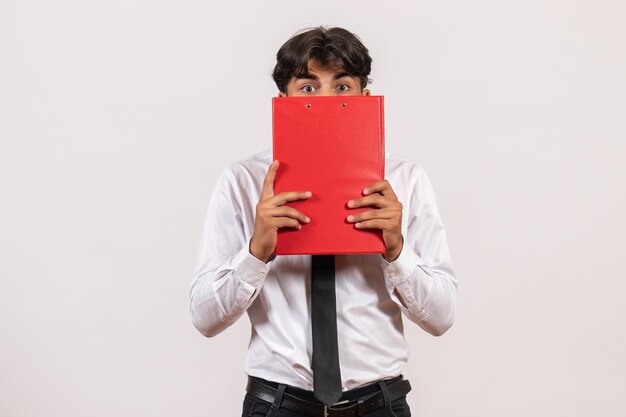 Front view male office worker holding red file on a white wall office work job human