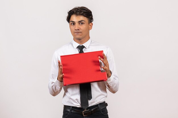 Front view male office worker holding red file on white wall office work job human