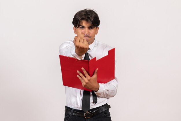 Front view male office worker holding red file on the white wall work office human job