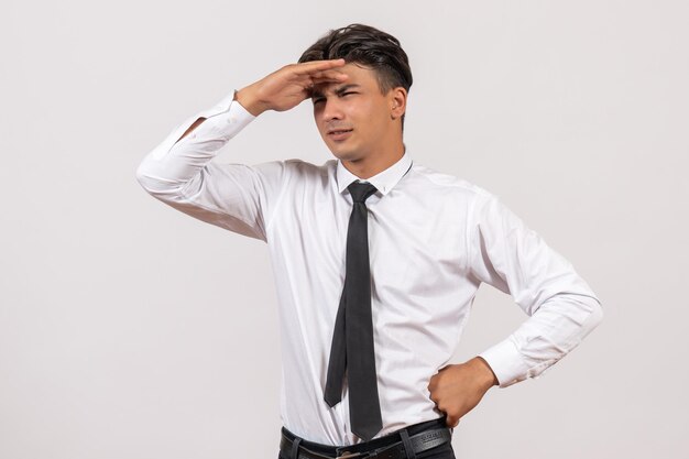 Front view male office worker looking at distance on white wall business work male job