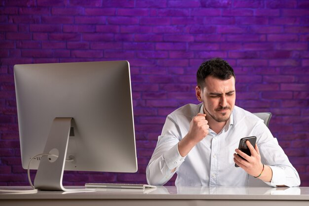 Front view male office worker sitting behind his working place and talking