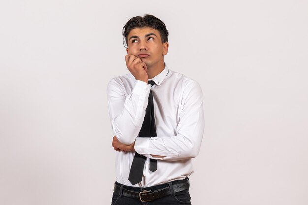 Front view male office worker thinking on white wall work male job business