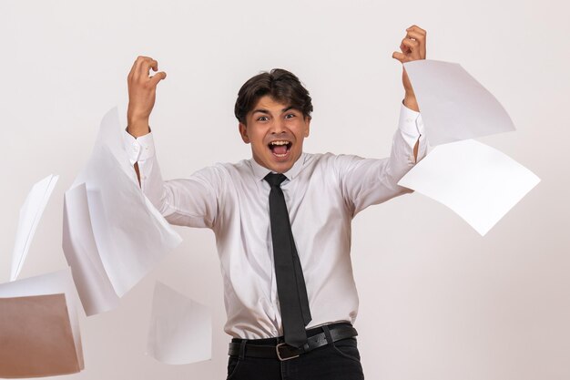 Front view male office worker throwing documents on white wall work human job male