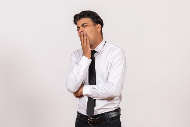 Front view male office worker yawning on white wall work male job business