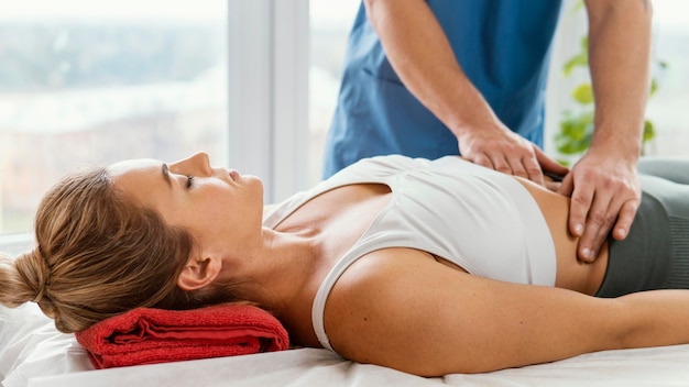 Front view of male osteopathic therapist checking female patient's abdomen