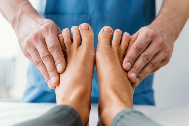여성 환자의 발가락을 검사하는 남성 정골 치료사의 전면보기