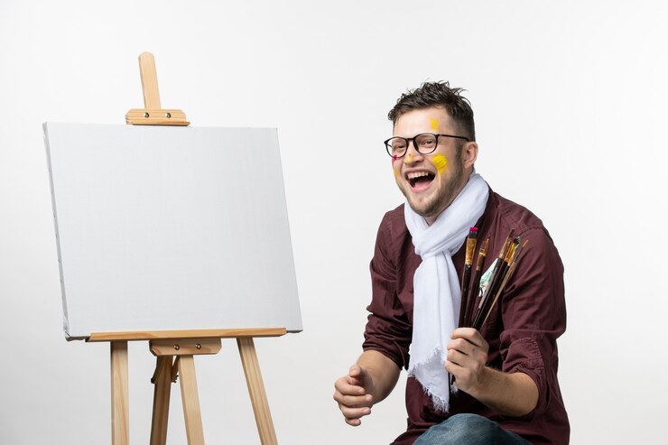Free Photo front view male painter holding paint brushes on white wall