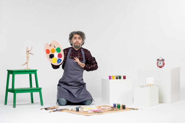 Вид спереди художник-мужчина готовится рисовать красками на белом фоне цветной человек, рисующий художник, рисующий художественную картину