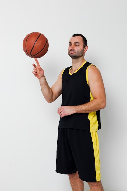 Вид спереди игрока мужского пола, балансируя баскетбол на одном пальце