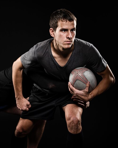 Вид спереди игрока мужского пола в регби, держащего мяч рукой