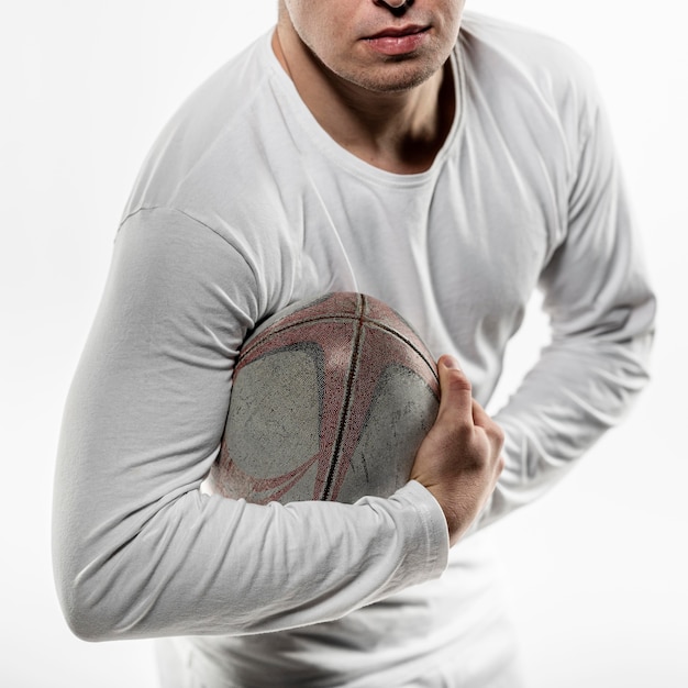 Free photo front view of male rugby player posing while holding ball