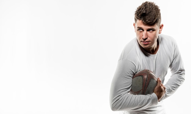 Front view of male rugby player posing with ball and copy space