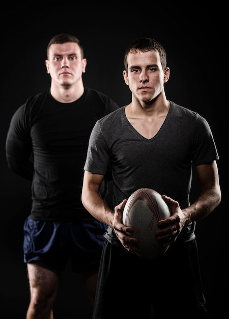 Front view of male rugby players posing with ball