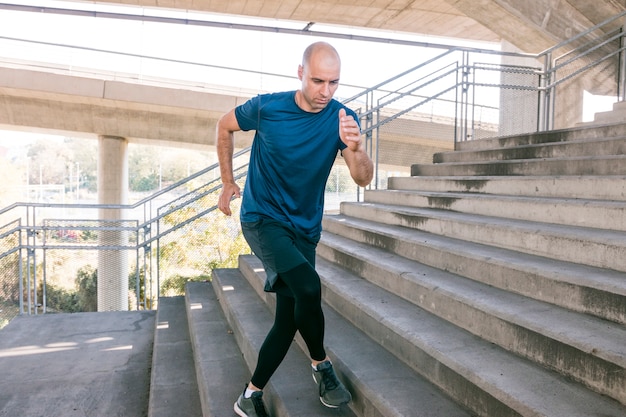 Front view of male runner sportsman running up city stairs jogging