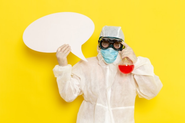 Free photo front view male scientific worker in special protective suit holding flask with red solution and white sign on yellow desk