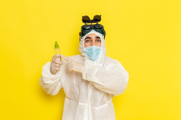 Free photo front view male scientific worker in special protective suit holding spray flask on light-yellow surface